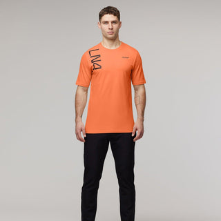 Man wearing an orange McLaren F1 Lando Norris Core T-shirt and black pants.