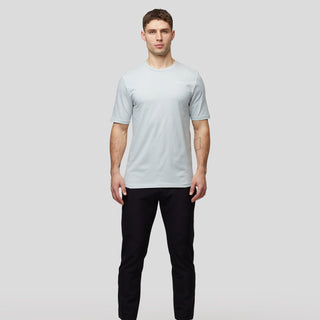 Man wearing a light blue McLaren F1 Lando Norris Core Essentials T-shirt and black trousers.